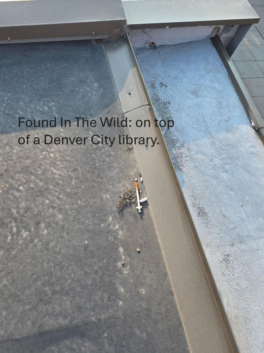A discarded syringe found on the flat roof surface of a commercial building.