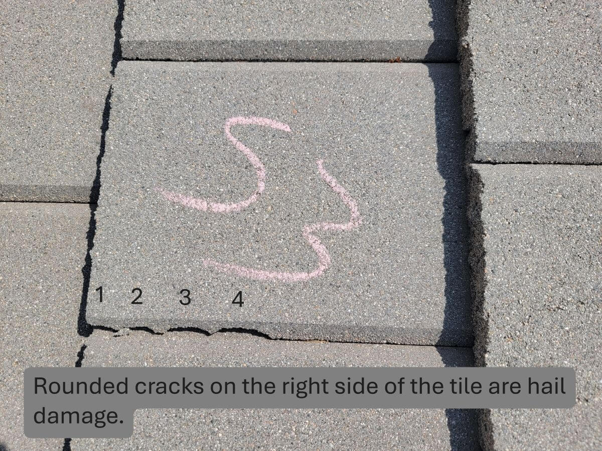 A rounded chip from hail impact on the corner of a concrete tile.
